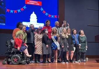 Group of 14 disability advocates standing together on stage