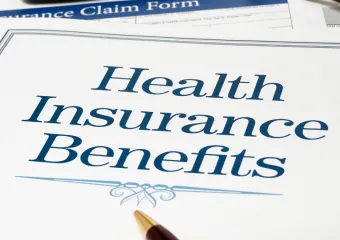 two sheets of paper; top one is a title page saying "Health Insurance Benefits" and is covering most of the second paper which is a Health Insurance Claim Form