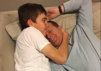 Stephen and his dad laying on the couch and hugging