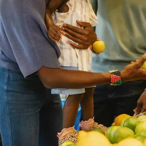 Black parents looking at produce in the supermarket with their young daughter