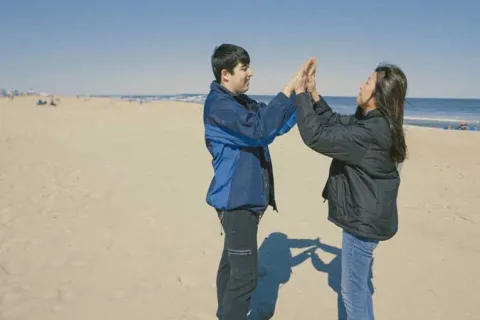 a mother and son high fiving on the beach