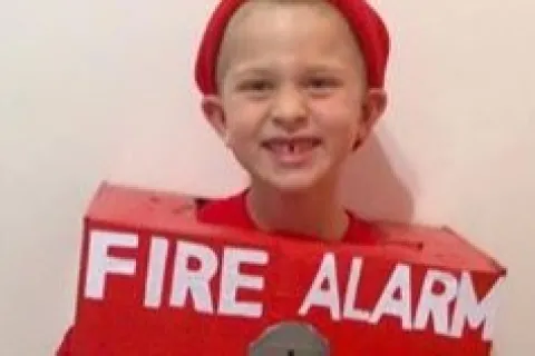 An autistic boy wearing a Halloween costume of a fire alarm