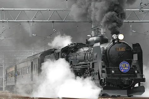 Black train on the rail with smoke underneath