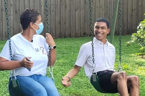 Blogger Michelle swinging on a swing set with her son, Justin. Justin has a big smile on his face.