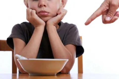 Child in front of a bowl of food that they don't want to eat