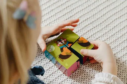 Child with blonde hair putting together blocks