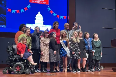 Group of 14 disability advocates standing together on stage