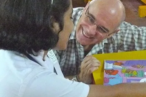 Jonathan Green kneeling down next to a table to talk to a young girl