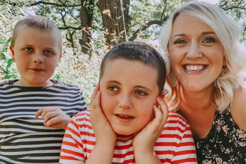 a blonde mother with her two sons wearing striped shirts