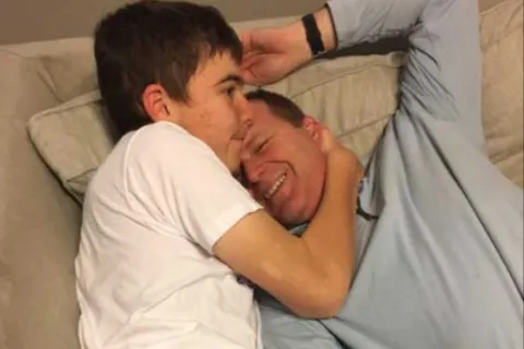 Stephen hugging his dad on the couch