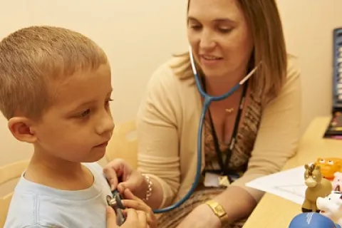 doctor using a stethoscope on a young blonde boy