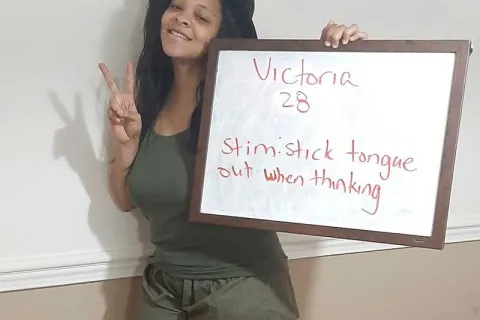 Victoria Handy holding a sign that describes how she stims