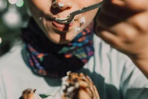 a child with cake on his face as he is eating