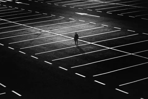 a person walking alone in an empty parking lot