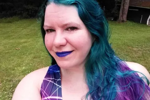 a woman with blue and purple hair, purple lipstick and a purple shirt