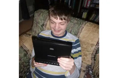 autistic child looking at an iPad and smiling