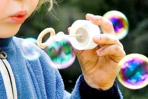 blonde toddler blowing bubbles