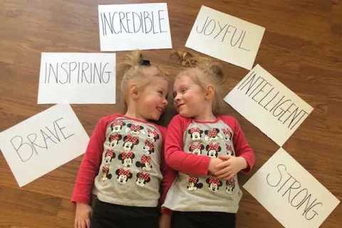 blonde toddlers laying on the floor wearing matching Minnie Mouse shirts