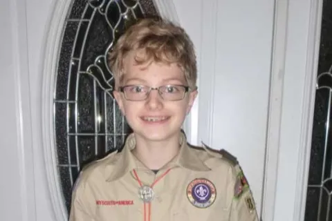 young boy with blonde hair and glasses wearing a Boy Scout uniform