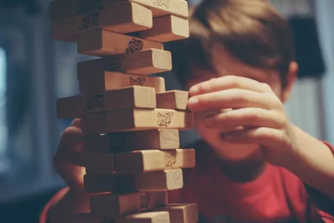 child in a red shirt playing Jenga