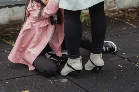 child in pink jacket sitting on the ground next to mother