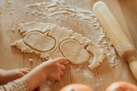 child making pumpkin shaped cookies