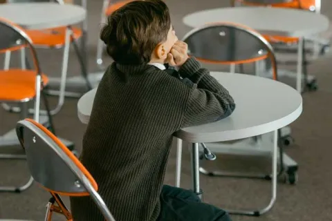 child sitting alone in an empty classroom