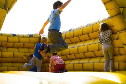 children jumping in a bounce house at a party