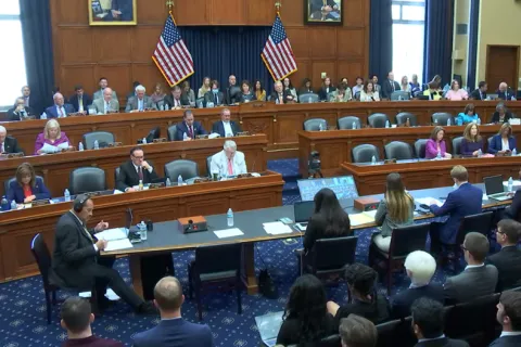 view of members of Congress seated in three rows in US Congressional hearing room