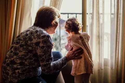 grandmother looking out the window with her granddaughter