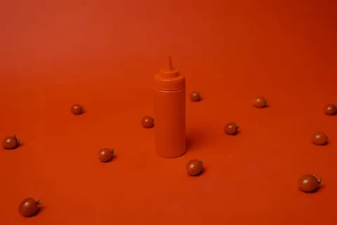 ketchup bottle on a red table with tomatoes