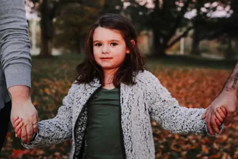 little girl holding her parents hands