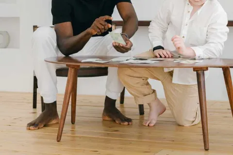 man and a child sitting at a wooden table playing cards