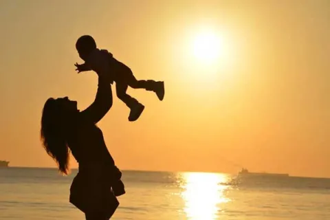 silhouette of a mom holding her child in the air