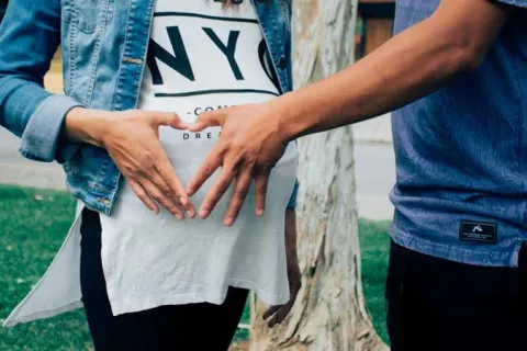 someone touching a pregnant woman's baby bump