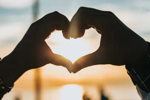 two people putting their hands together to make a heart shape