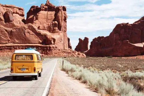 yellow camper van driving through mountains