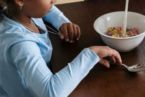 young girl eating cereal at the table