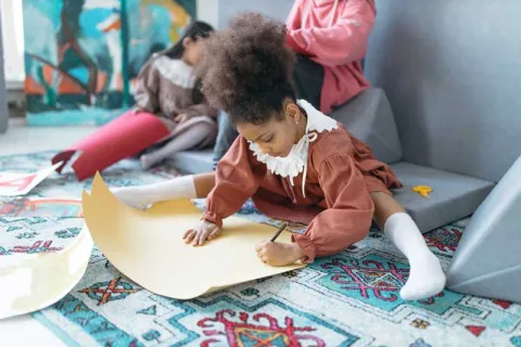 young girl holding a pencil and writing on yellow paper