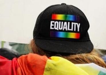 A person wearing a backwards hat that says Equality with the Pride flag