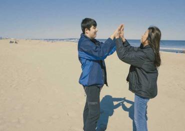 a mother and son high fiving on the beach