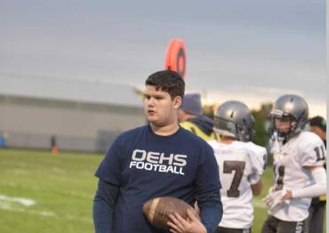 Andrew holding a football and wearing an OEHS football shirt