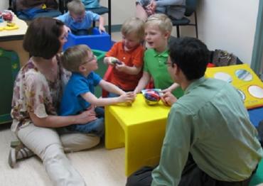 Dr. Lonnie Zwaigenbaum sitting on the floor with children