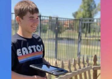 A boy with a shirt that says Easton and a iPad smiles off camera