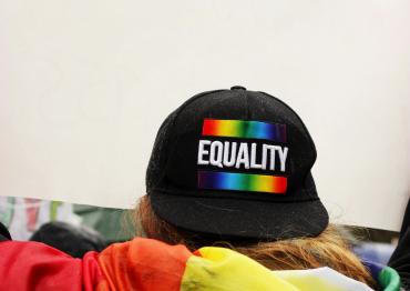 A person wearing a backwards hat that says Equality with the Pride flag