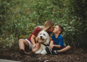 a mother, son and their dog sitting in the forest