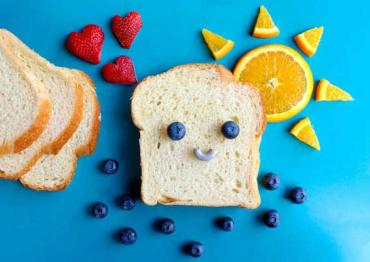 a piece of bread with fruit on top to make a smiley face