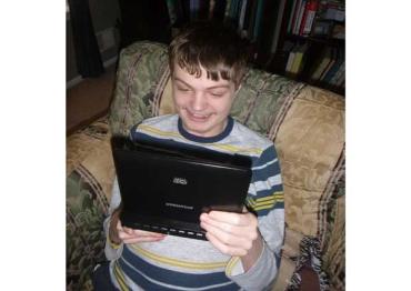 autistic child looking at an iPad and smiling