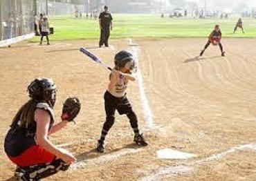 a toddler wearing a yellow team shirt batting during a baseball game