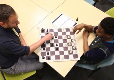 Mount Sinai Adolescent Health Center worker playing chess with a teen